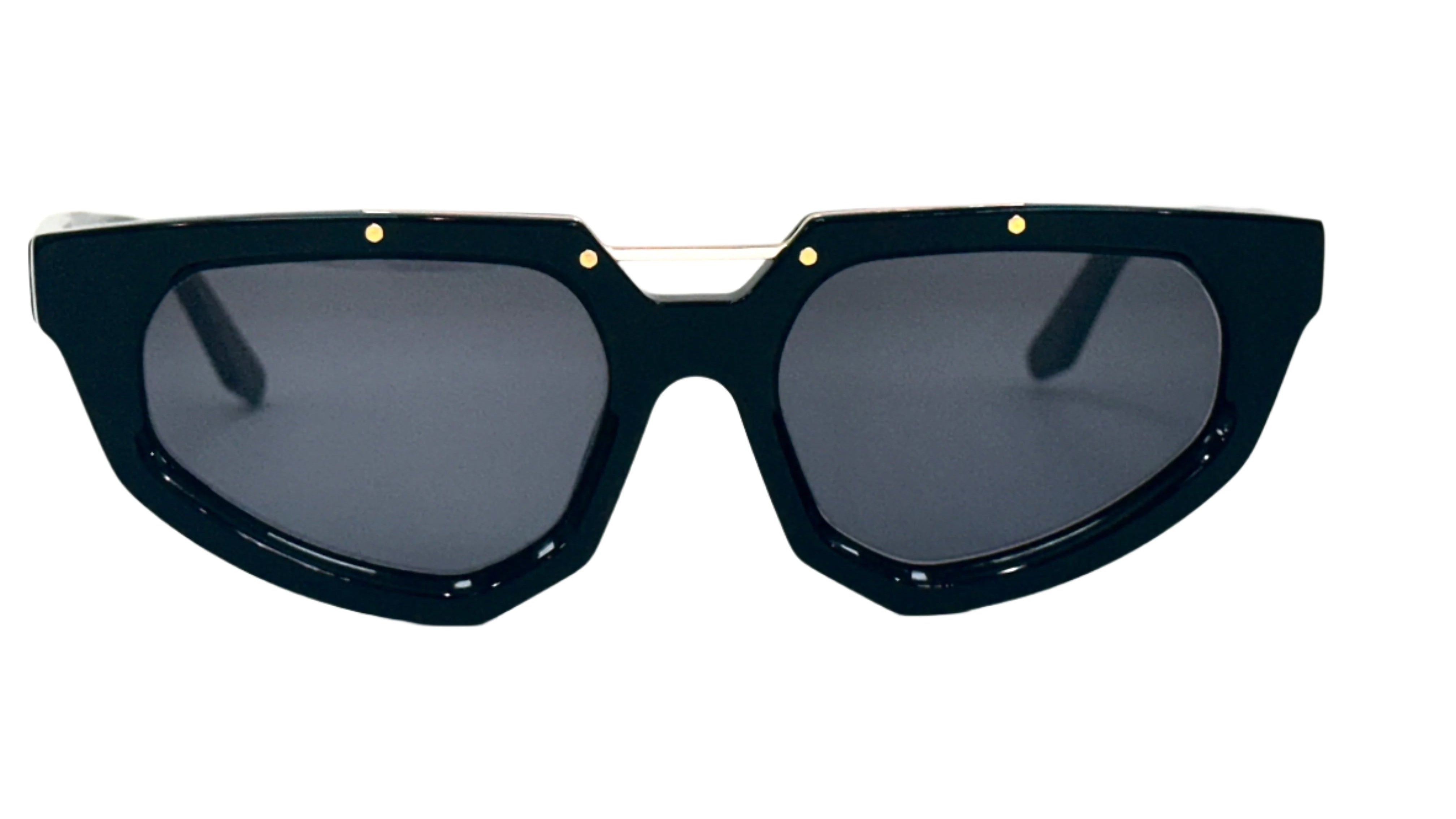 A close-up view of black stylish sunglasses with an angular design and grey lenses. The frame features small gold accents, adding a touch of elegance to the modern, edgy style.