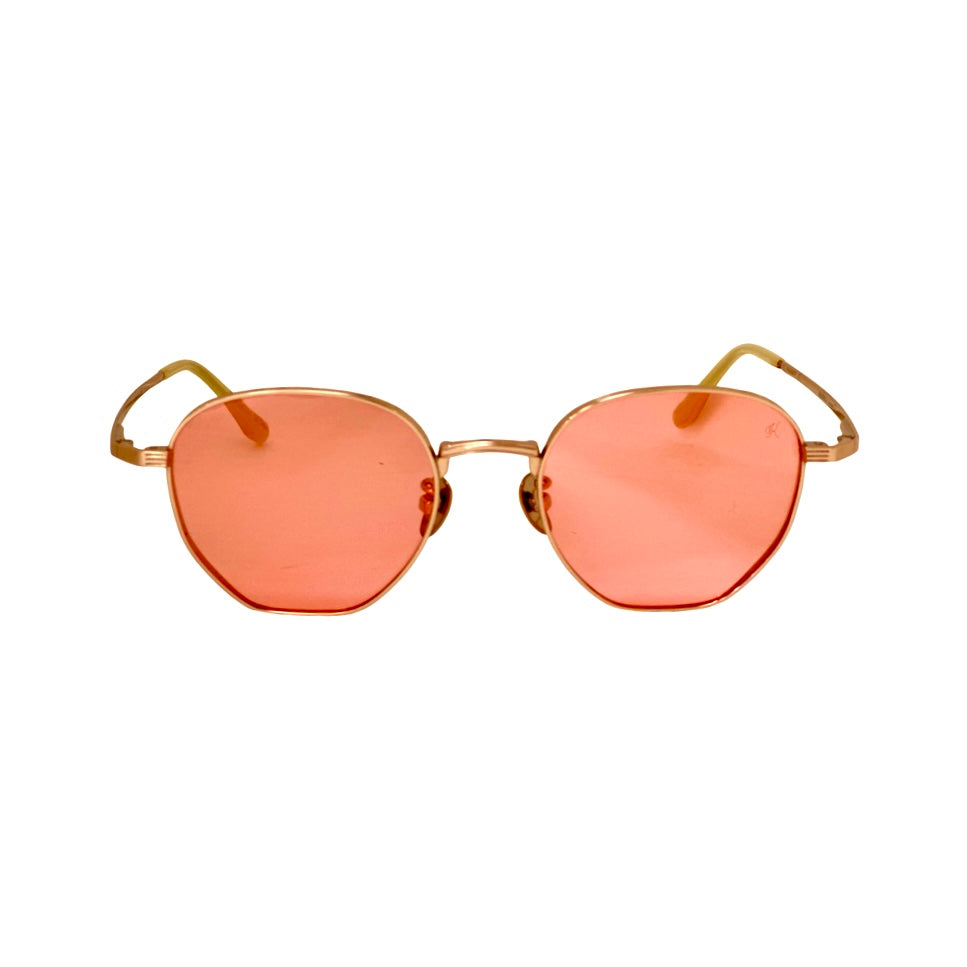 Sunglasses with gold frame and pink-tinted lenses - Titanium nose pads preventing slips during outdoor activity - Anti-glare lenses eliminating reflections on a phone screen.