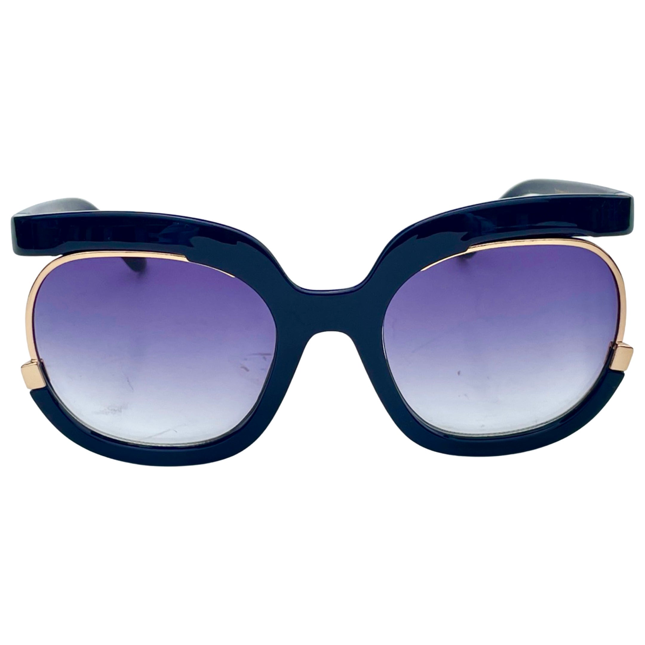 Front view of oversized sunglasses featuring a navy blue frame and gradient purple lenses. The sunglasses have gold detailing along the edges.