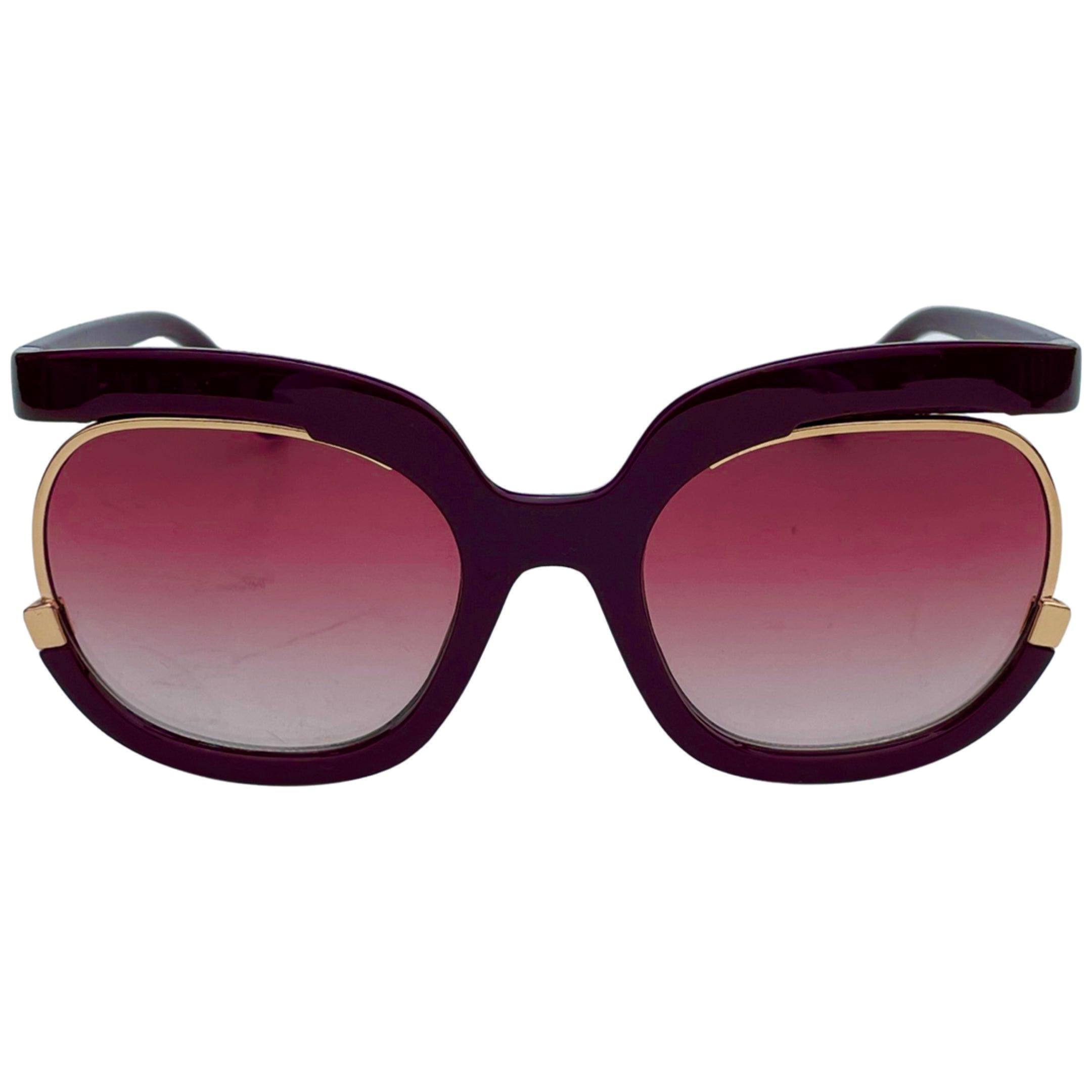 A pair of stylish sunglasses with large, butterfly-shaped frames. The frames are a deep purple color with gold accents, and the lenses transition from a light pink at the top to a darker pink at the bottom